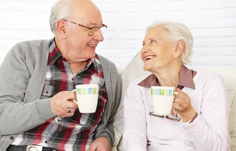Two older adults sharing coffee and conversation